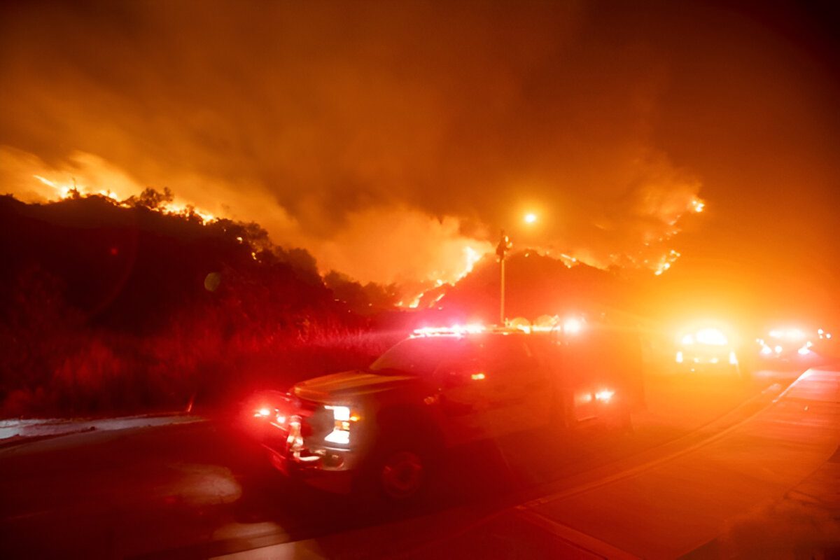 Emergency vehicles responding to a large wildfire at night.