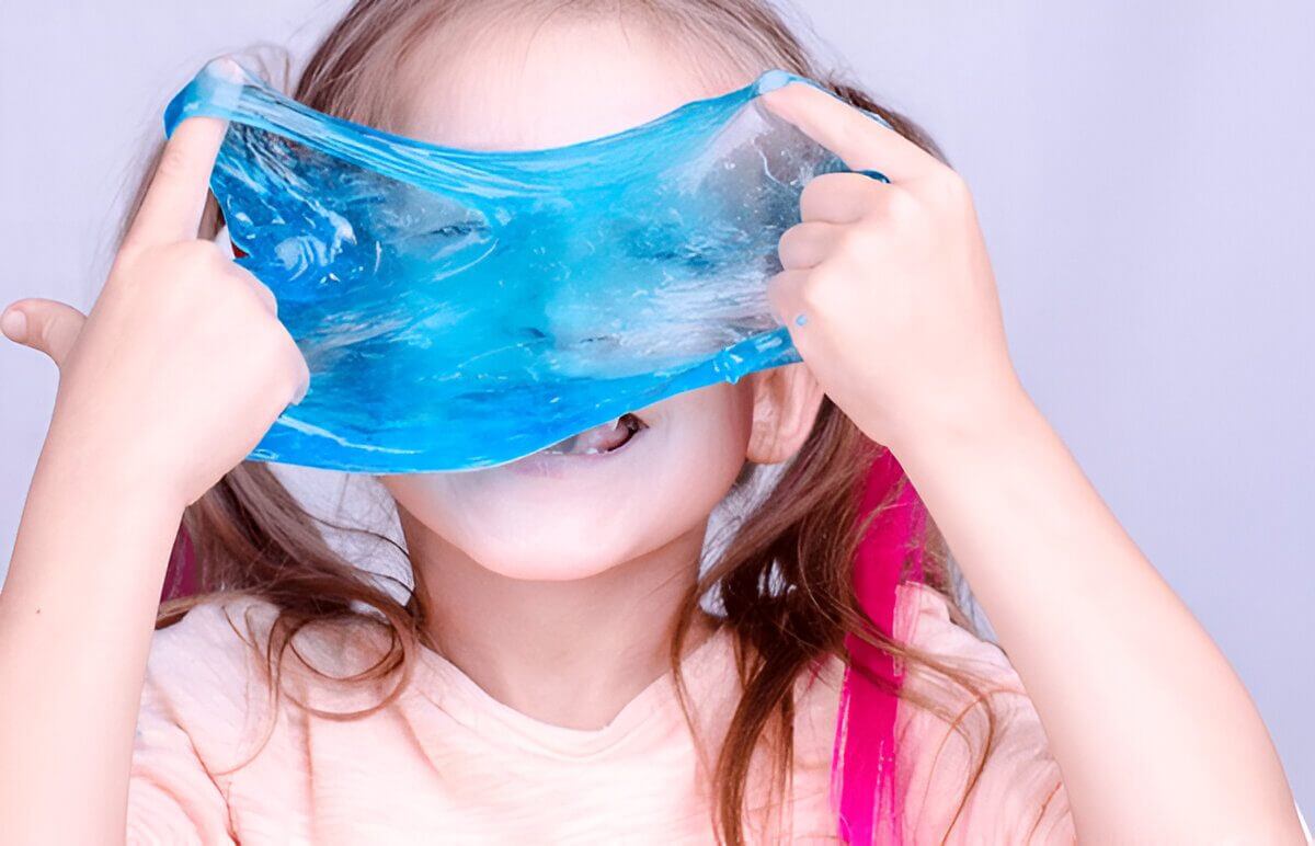 Girl playfully covering her face with stretchy blue slime.